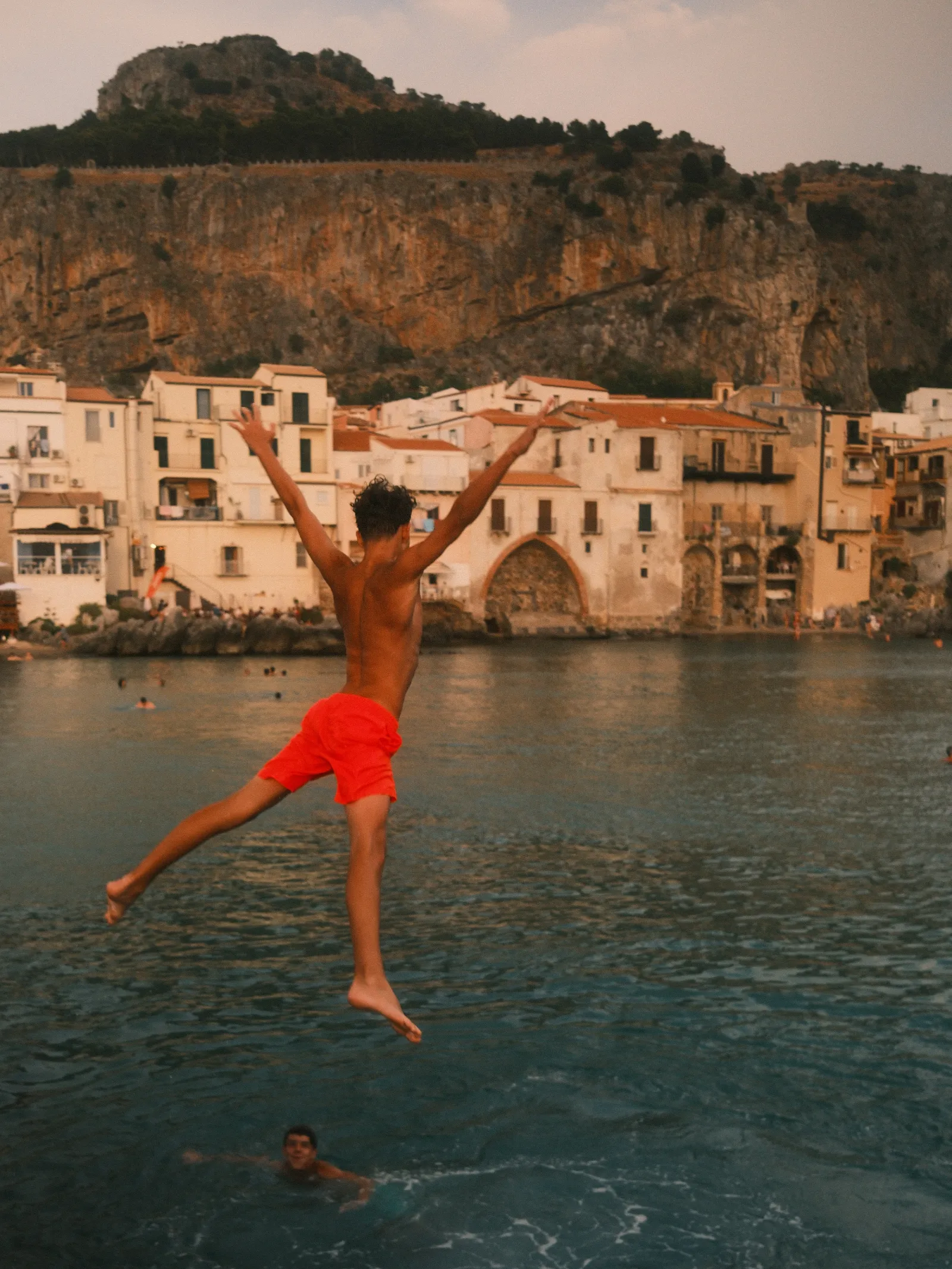 A kid jumping into the water in Cefalù