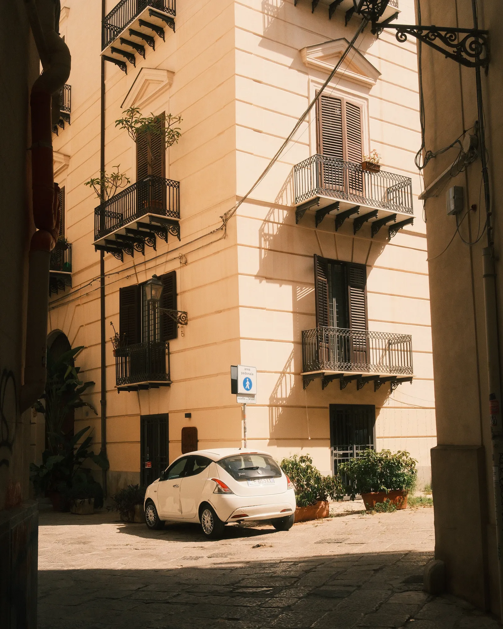 A quiet street in Palermo A white car parked at a corner in Palermo, Sicily