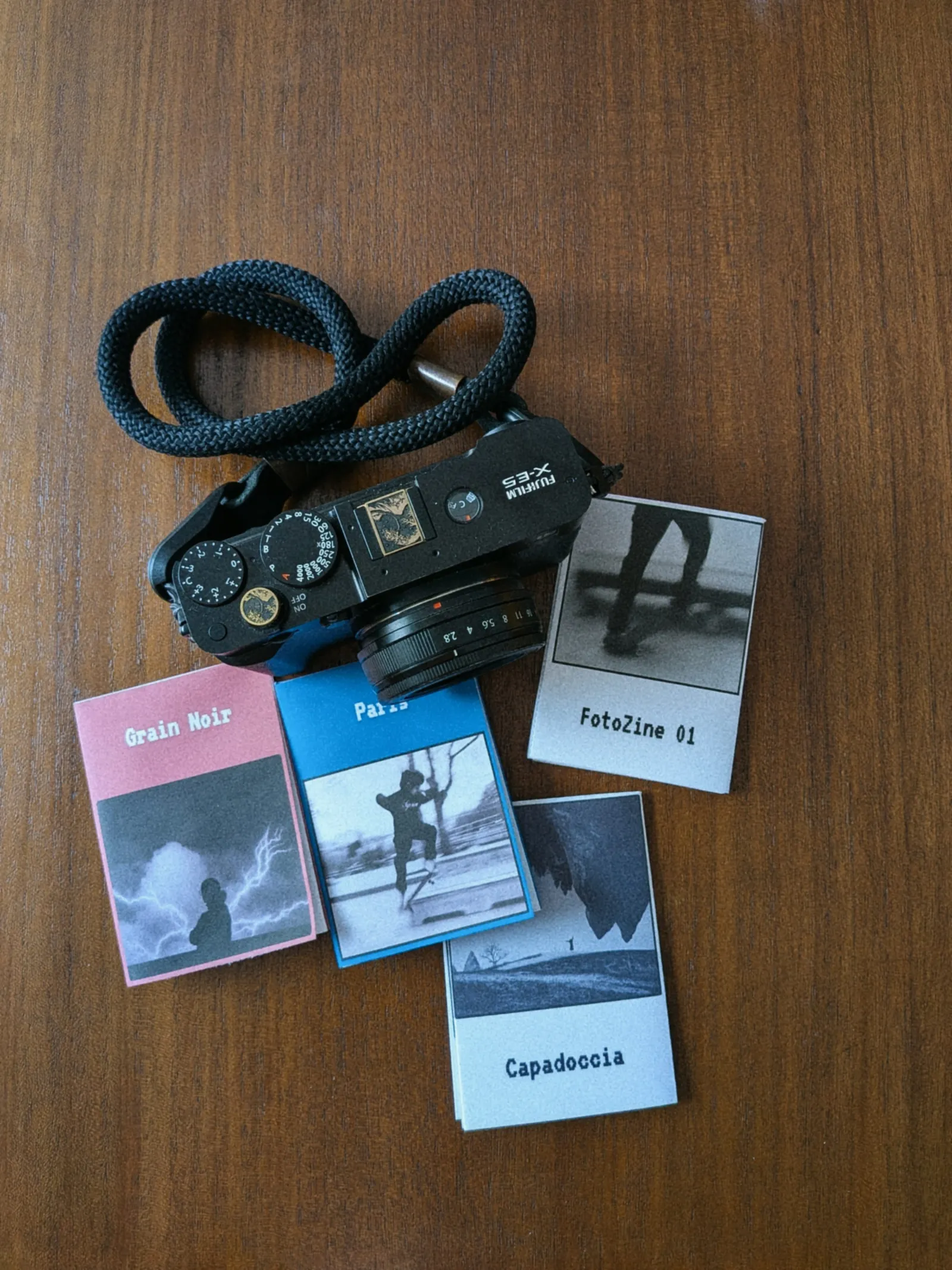Fujifilm camera next to a series of handmade pocket photo zines