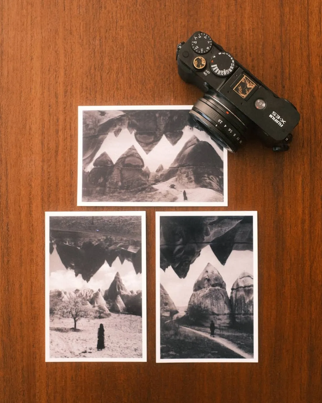 Three black and white Cappadocia prints from the Canon Selphy CP1500 next to a Fujifilm X-E5 on a wooden desk