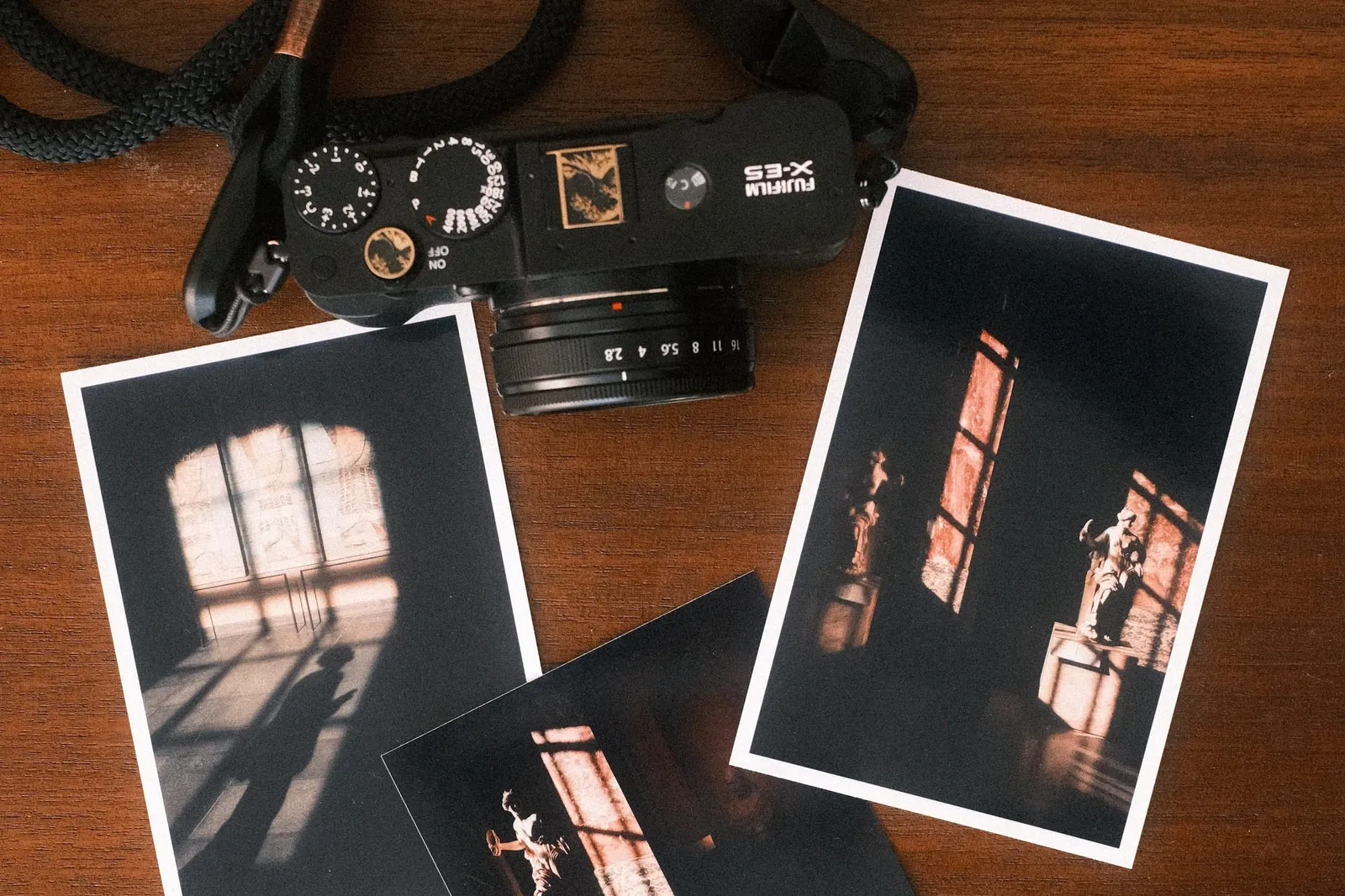 Three Canon Selphy CP1500 prints of a sunlit museum interior laid out next to a Fujifilm X-E5